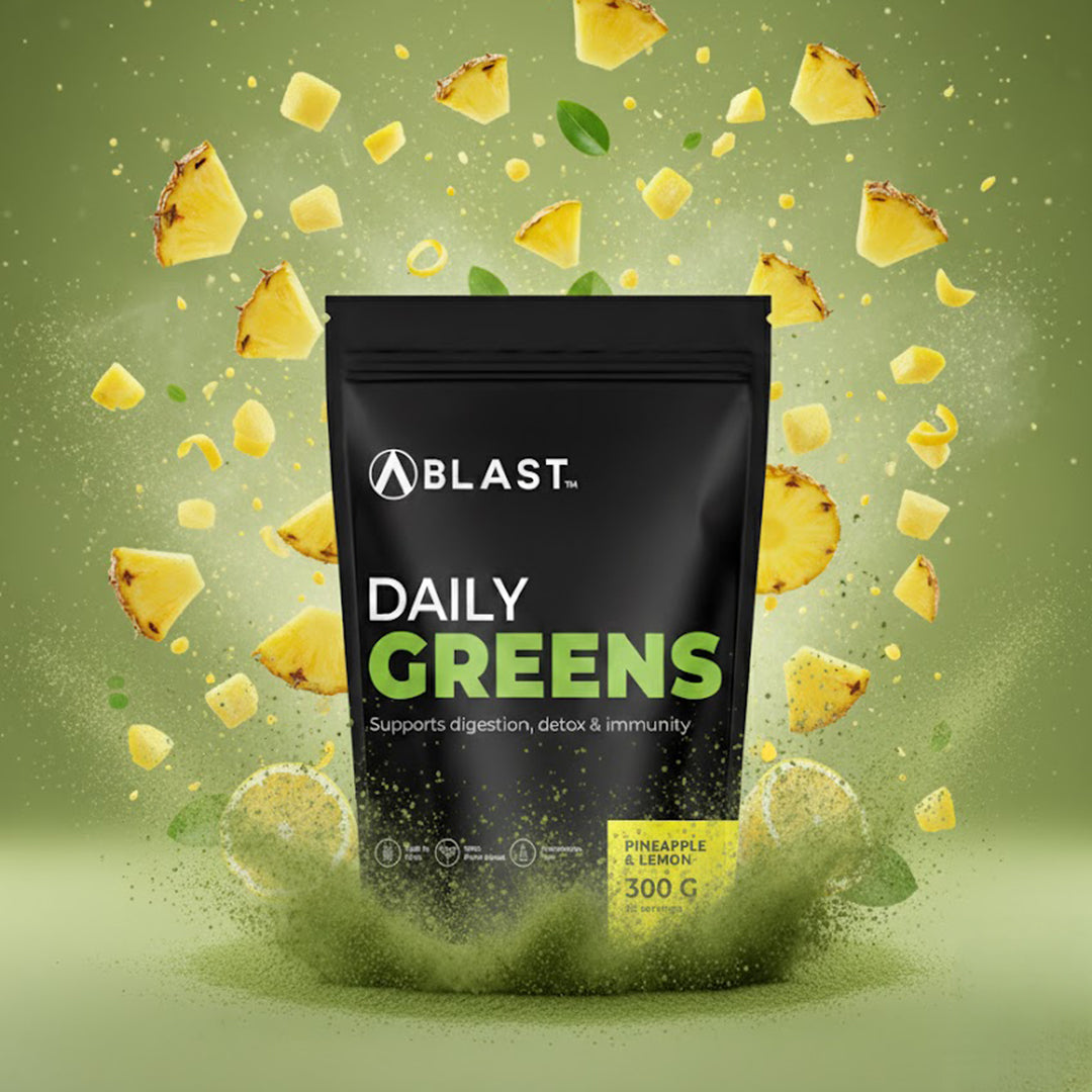 Bag of 'Blast Daily Greens' supplement with flying pineapple pieces on a green background