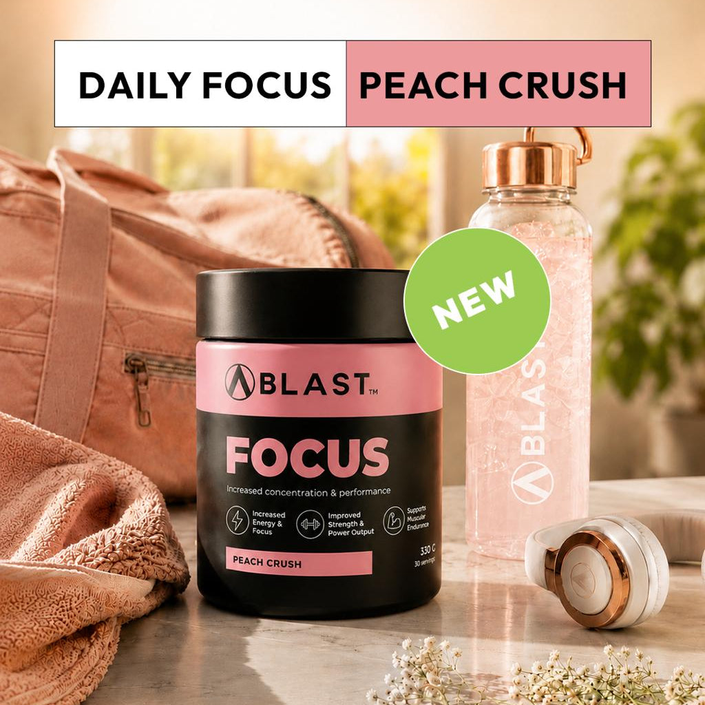 Blast Focus supplement container with peach crush flavor on a marble surface with a pink bag and water bottle in the background.