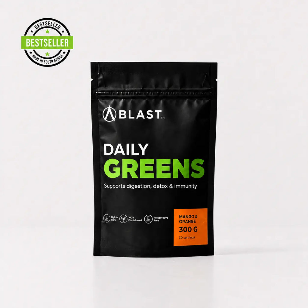 A black stand-up pouch of BLAST Daily Greens supplement powder on a light gray background, with a green and black Bestseller badge in the top-left corner. The pouch features white and bright green text, and an orange label indicating Mango & Orange flavor and 300g weight.