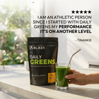 A Blast Daily Greens package with a glass of green juice on a table, outdoors.