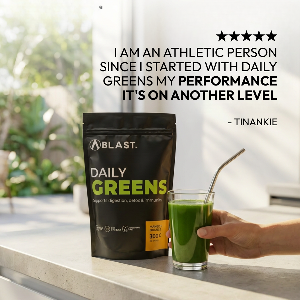 A Blast Daily Greens package with a glass of green juice on a table, outdoors.