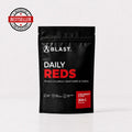 A black stand-up pouch of BLAST Daily Reds dietary supplement, strawberry & kiwi flavor, 300g. The packaging features white and red text, and a red 'Bestseller' badge is shown in the top-left corner.
